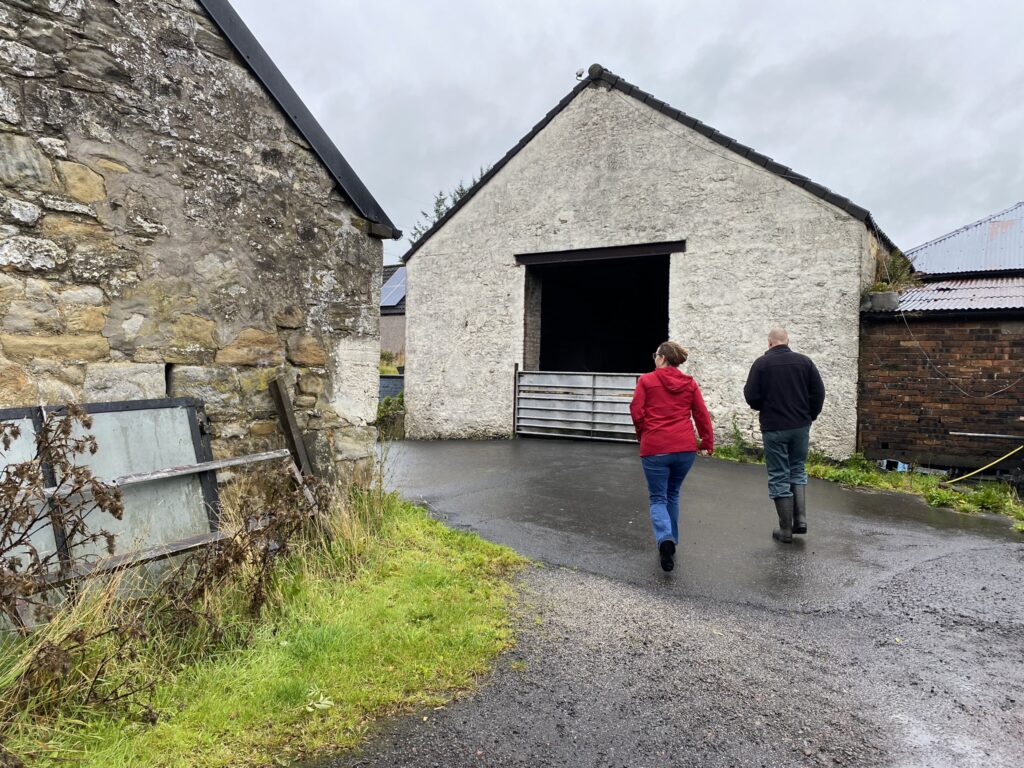 Man and woman walking in a barn area